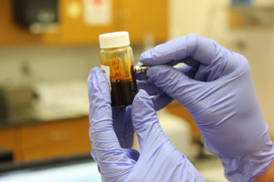 Hände in Laborhandschuhen mit Reagenzglas